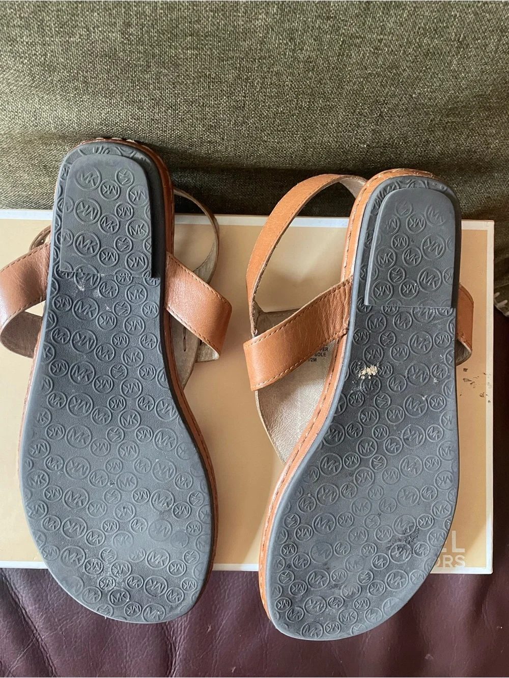 Michael Kors tan leather thong sandals feature a polished gold-tone MK log